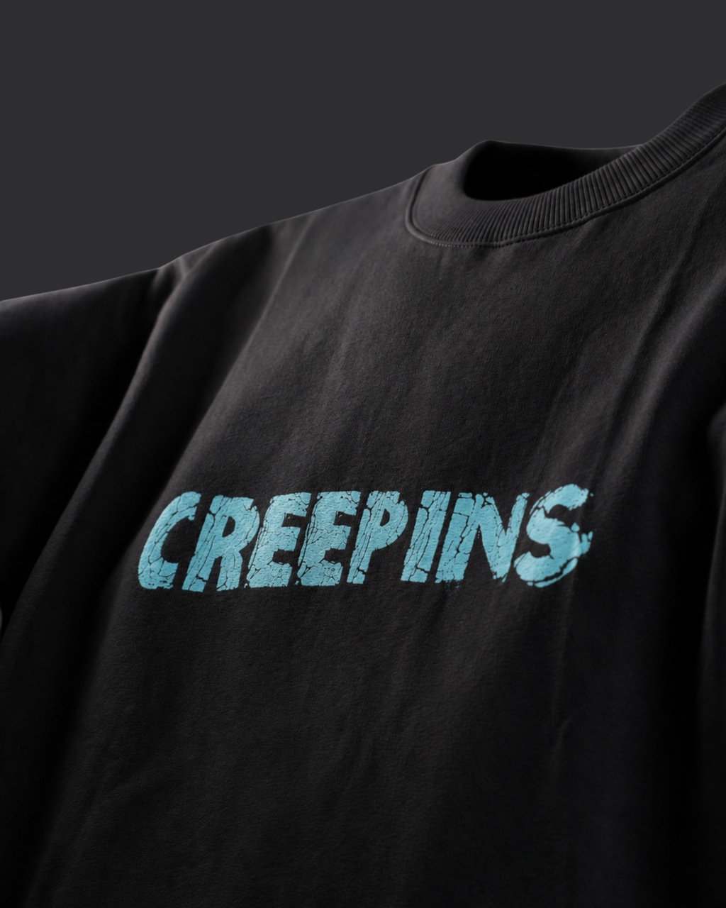 A close-up of a black crewneck sweatshirt featuring the word 'CREEPINS' printed across the chest in a distressed light blue font.