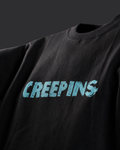 A close-up of a black crewneck sweatshirt featuring the word 'CREEPINS' printed across the chest in a distressed light blue font.