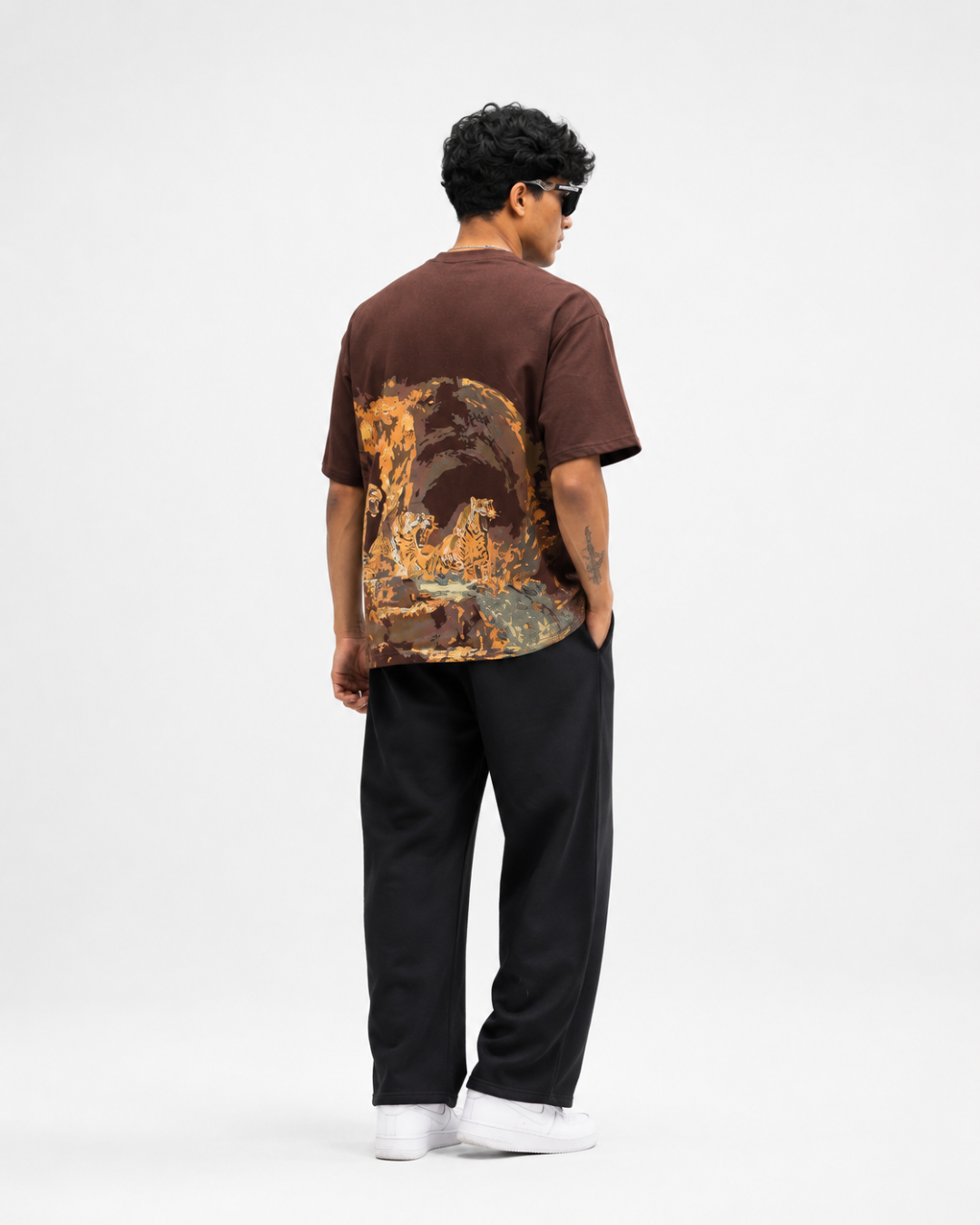 A man is shown from the back wearing a CREEPINS t-shirt with a large orange and yellow cave graphic print on the back, paired with black sweatpants and white sneakers, against a plain white studio background.